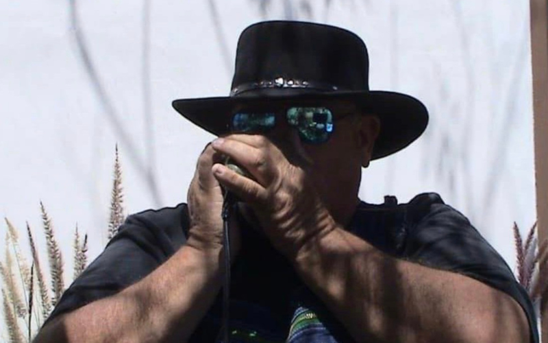 Photo of Dan McDowell playing harmonica in a black cowboy hat