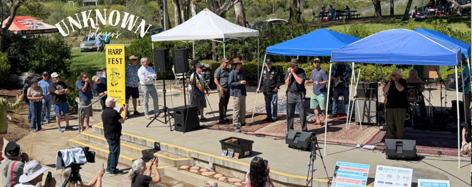 Musicians performing under blue and white canopy tents at Spring Harp Fest with a yellow banner displaying the logo.